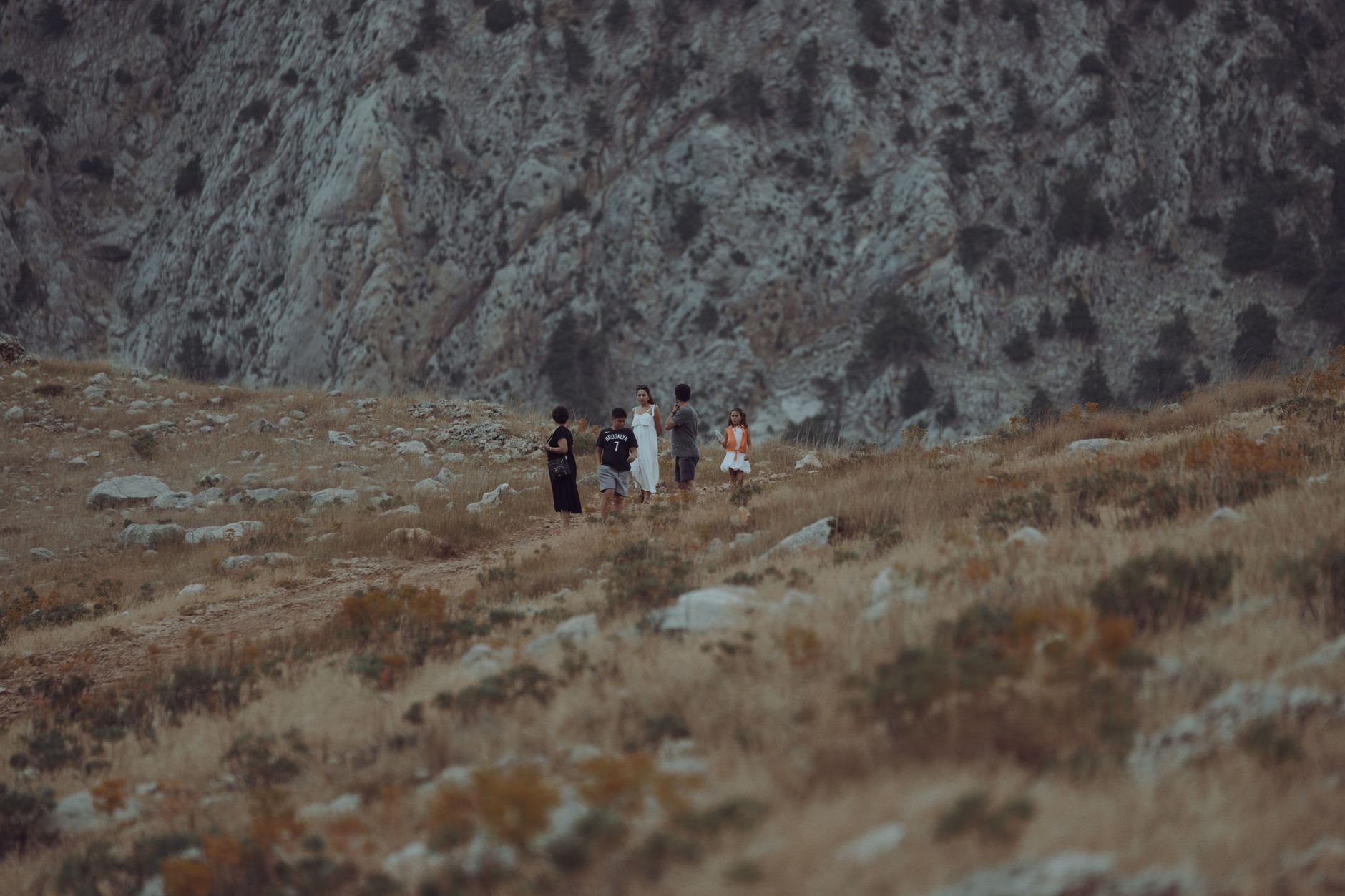 A small group of friends hiking on a rocky mountain trail, surrounded by a rugged landscape.